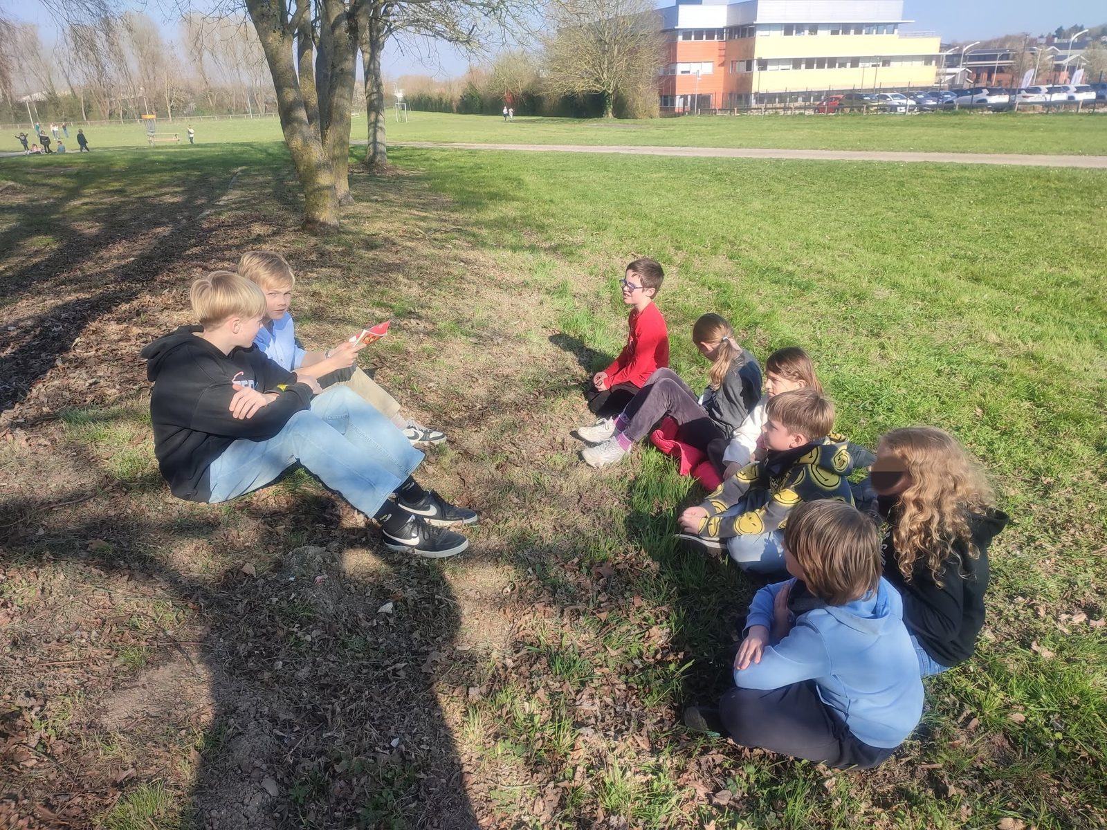 Des élèves lisent assis dans l'herbe, sur le campus