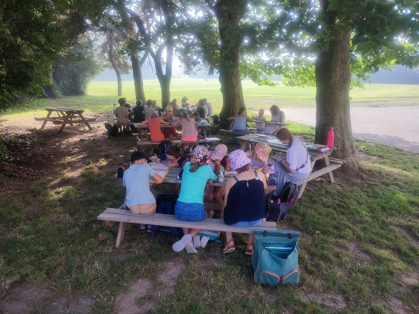 Dessin en plein air Des élèves dessinent sur des tables de pique-nique, à l'ombre des arbres