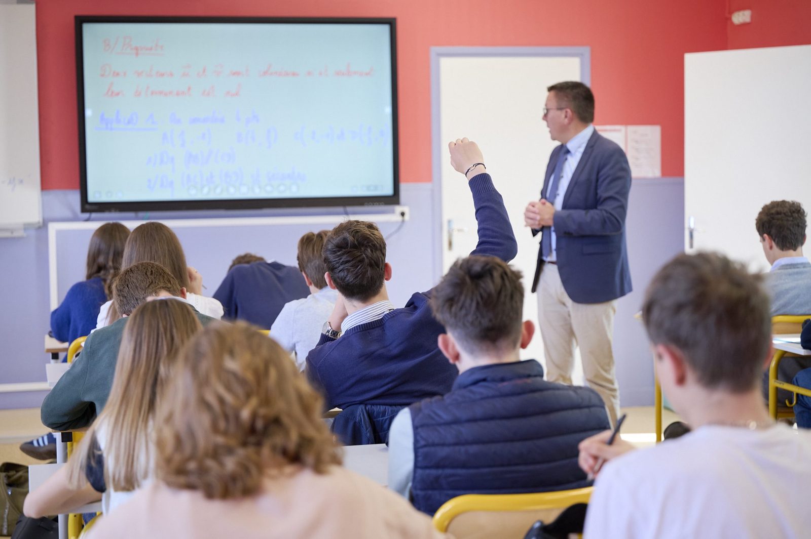 Un élève lève la main pendant un cours au lycée