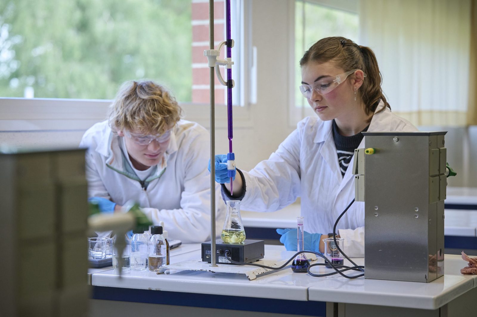 Deux lycéens en blouse réalisent un titrage en chimie